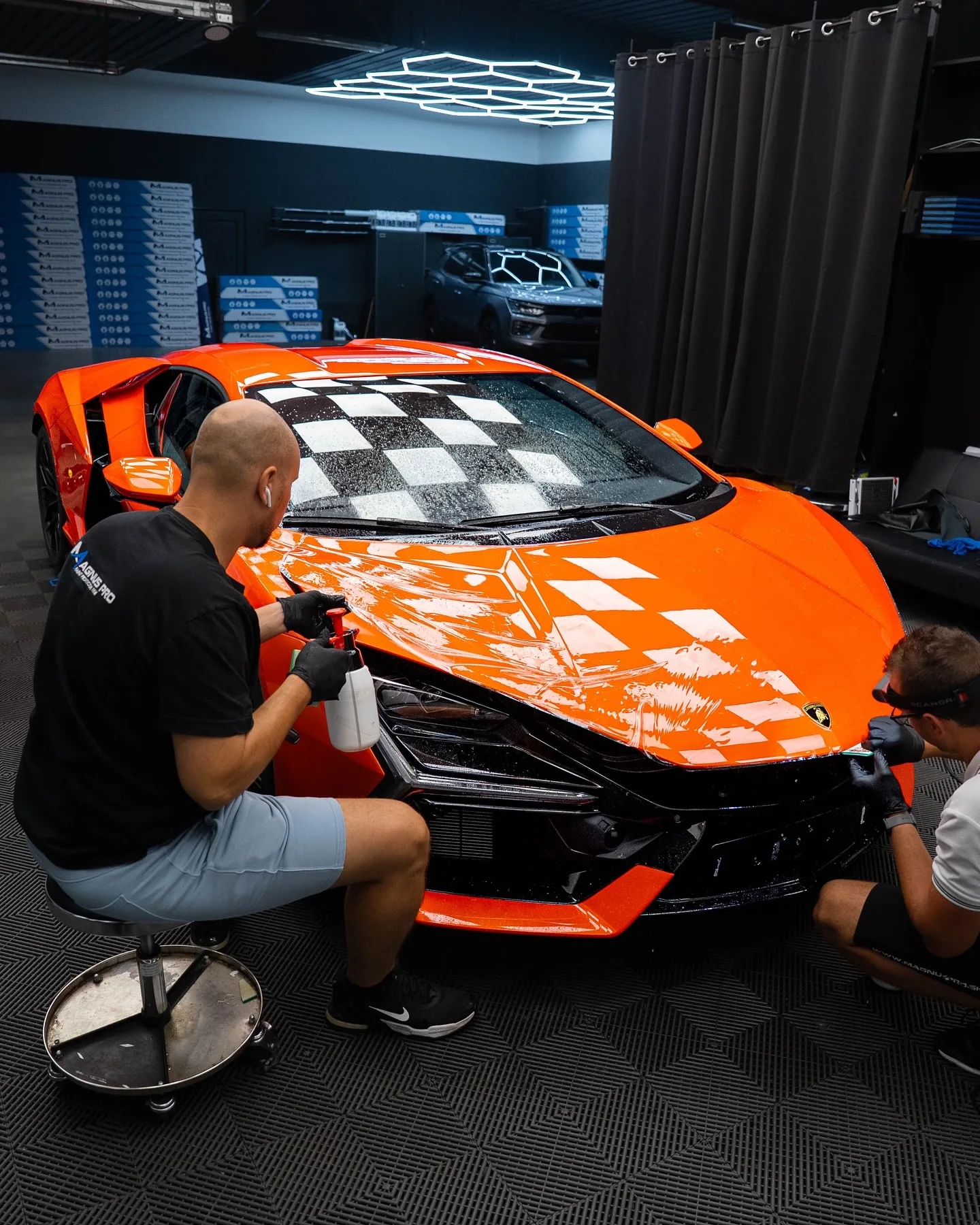 Aplikátor kladie ochrannú fóliu Magnus Pro na prednú časť oranžového Lamborghini Revuelto