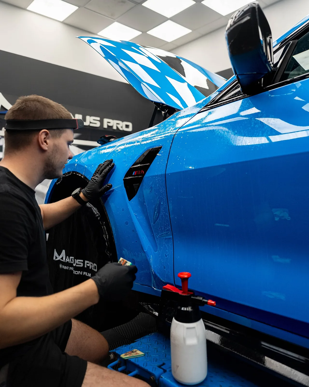 Aplikátor Magnus Pro uhládza ochrannú fóliu na blatníku modrého BMW M4 CS