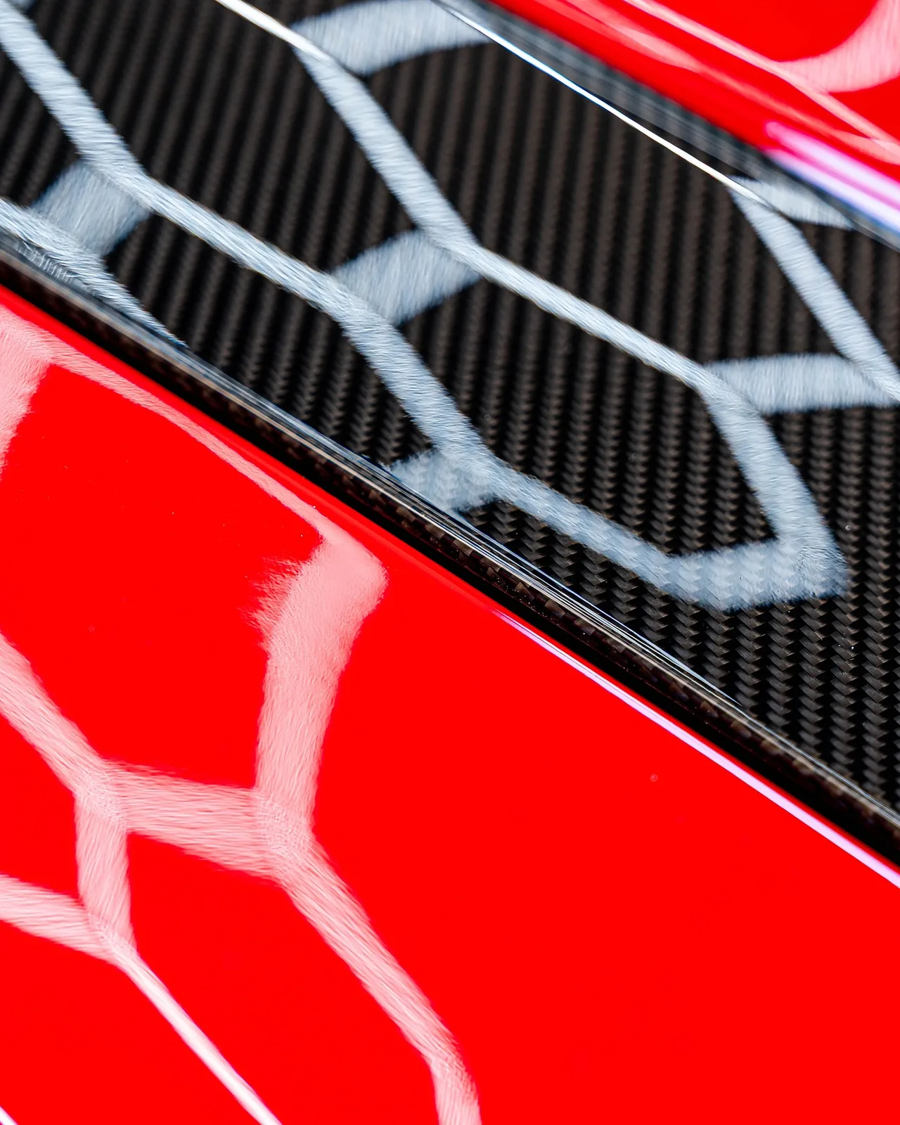 Detail lesku: odraz svetiel v červenom laku a karbóne Porsche 911 GT3 RS pod fóliou Magnus Pro